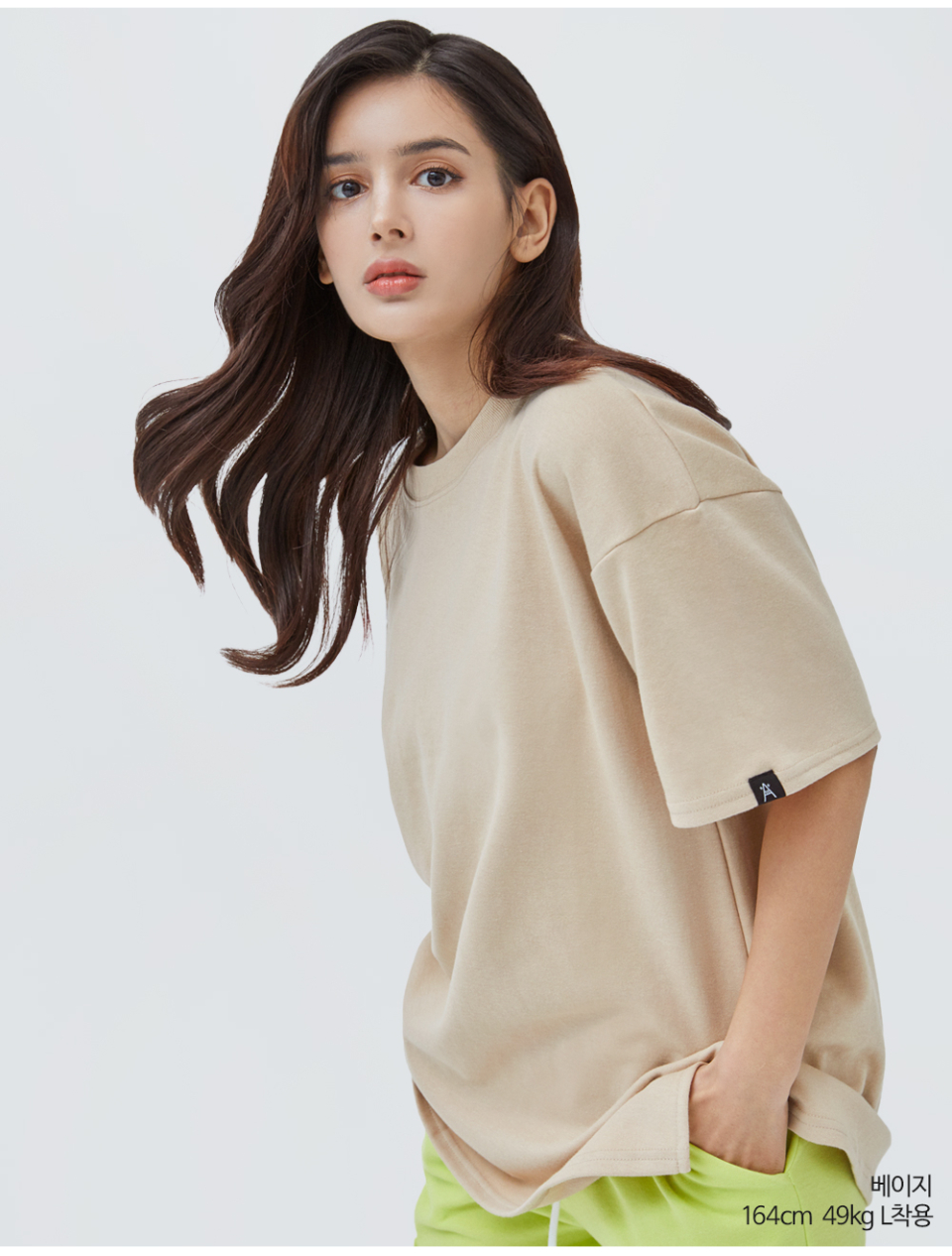 베이지색옷 팔에 포인트로 라벨이 붙어있는 옷을 입은 여자사진