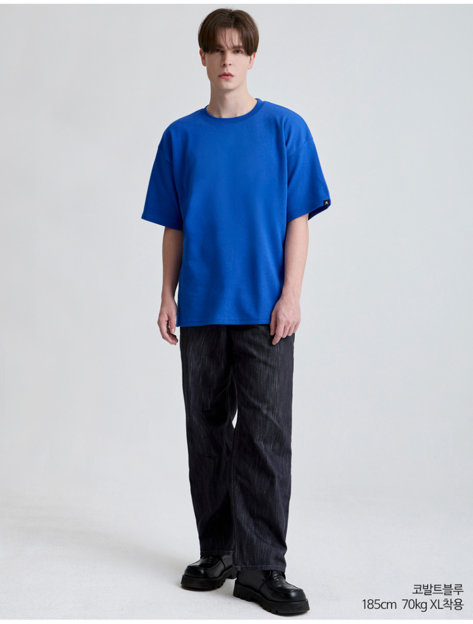 코발트블루색옷 팔에 포인트로 라벨이 붙어있는 옷을 입은 남자사진