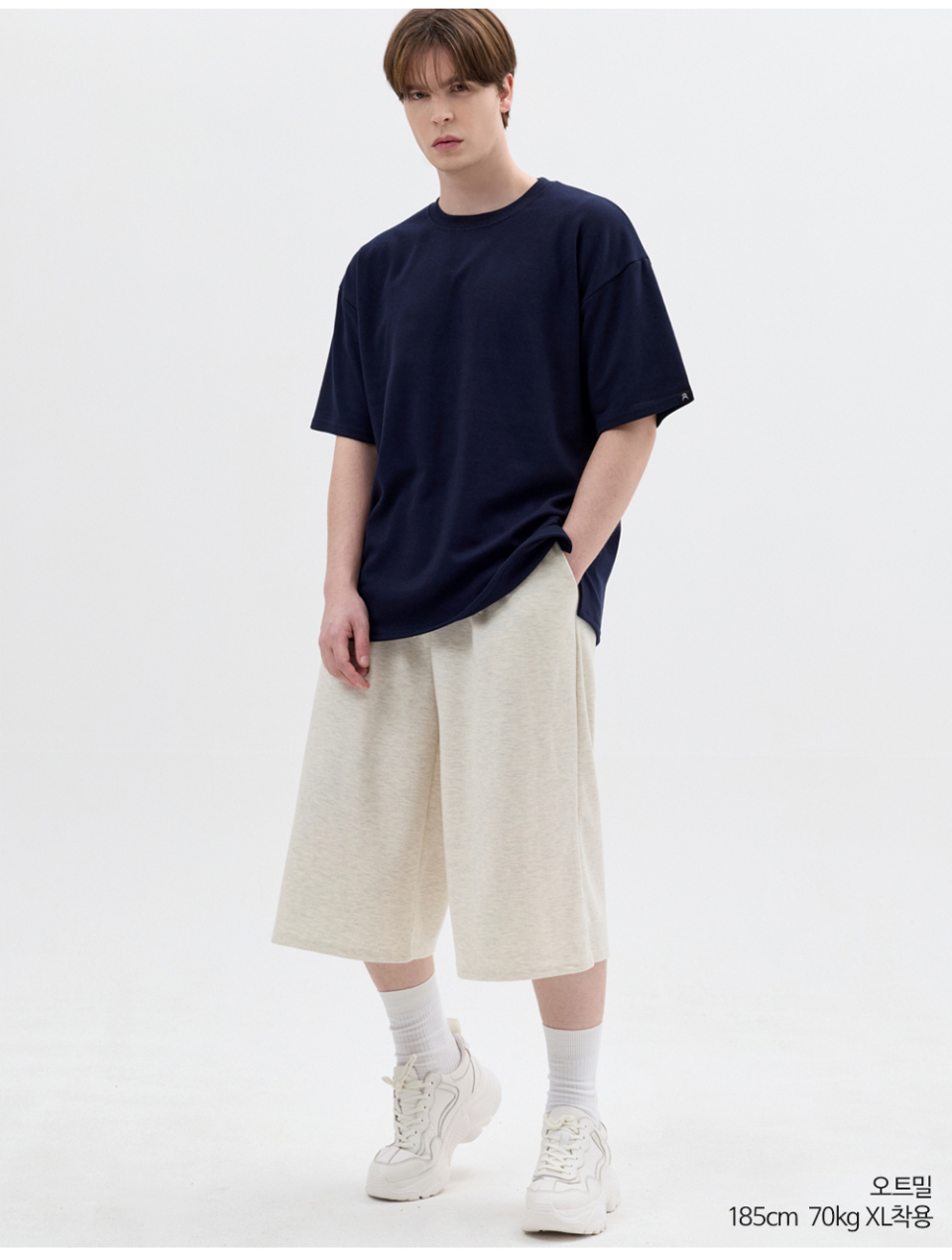 오트밀색상 8부 원턱 버뮤다 쇼츠를 입은 남자 사진