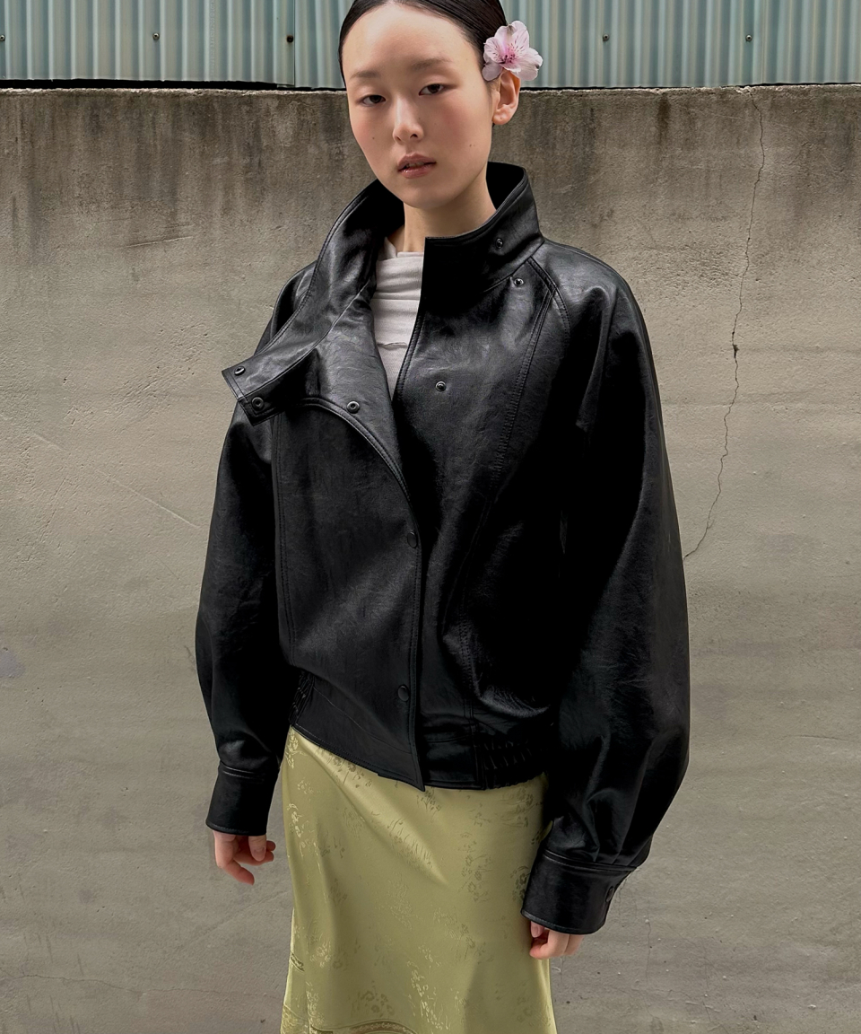 모델이 검정색 와이드 카라 인조 가죽 자켓을 입고있다.