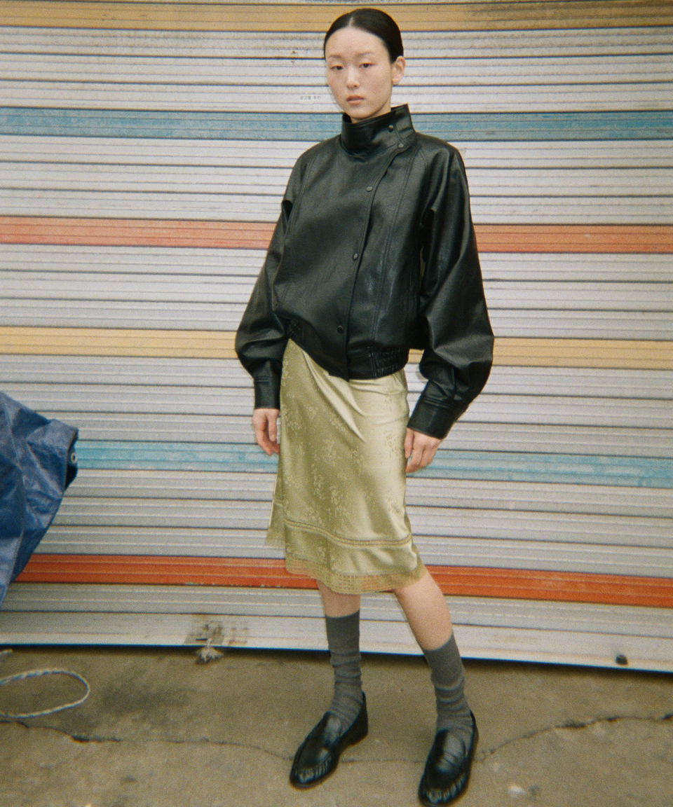 모델이 검정색 와이드 카라 인조 가죽 자켓을 입고있다.