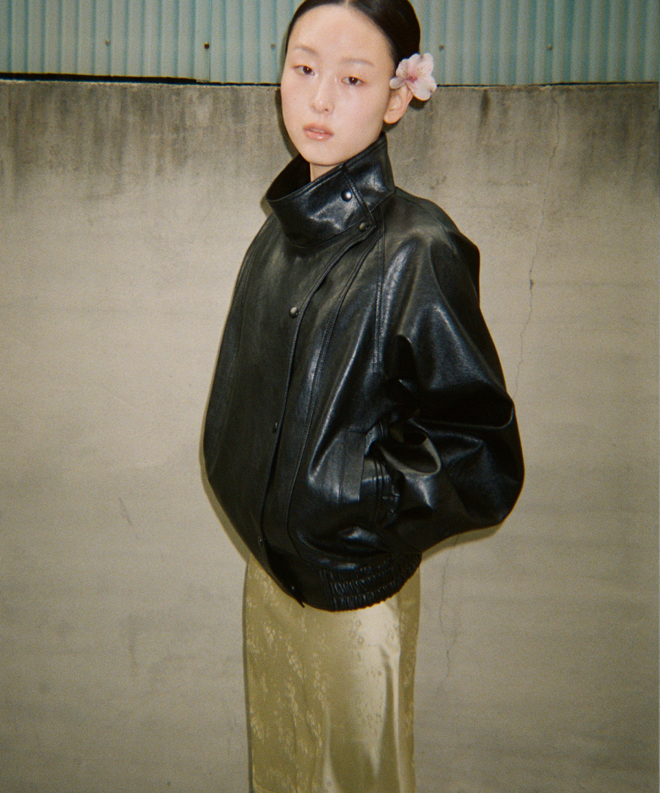 모델이 검정색 와이드 카라 인조 가죽 자켓을 입고있다.