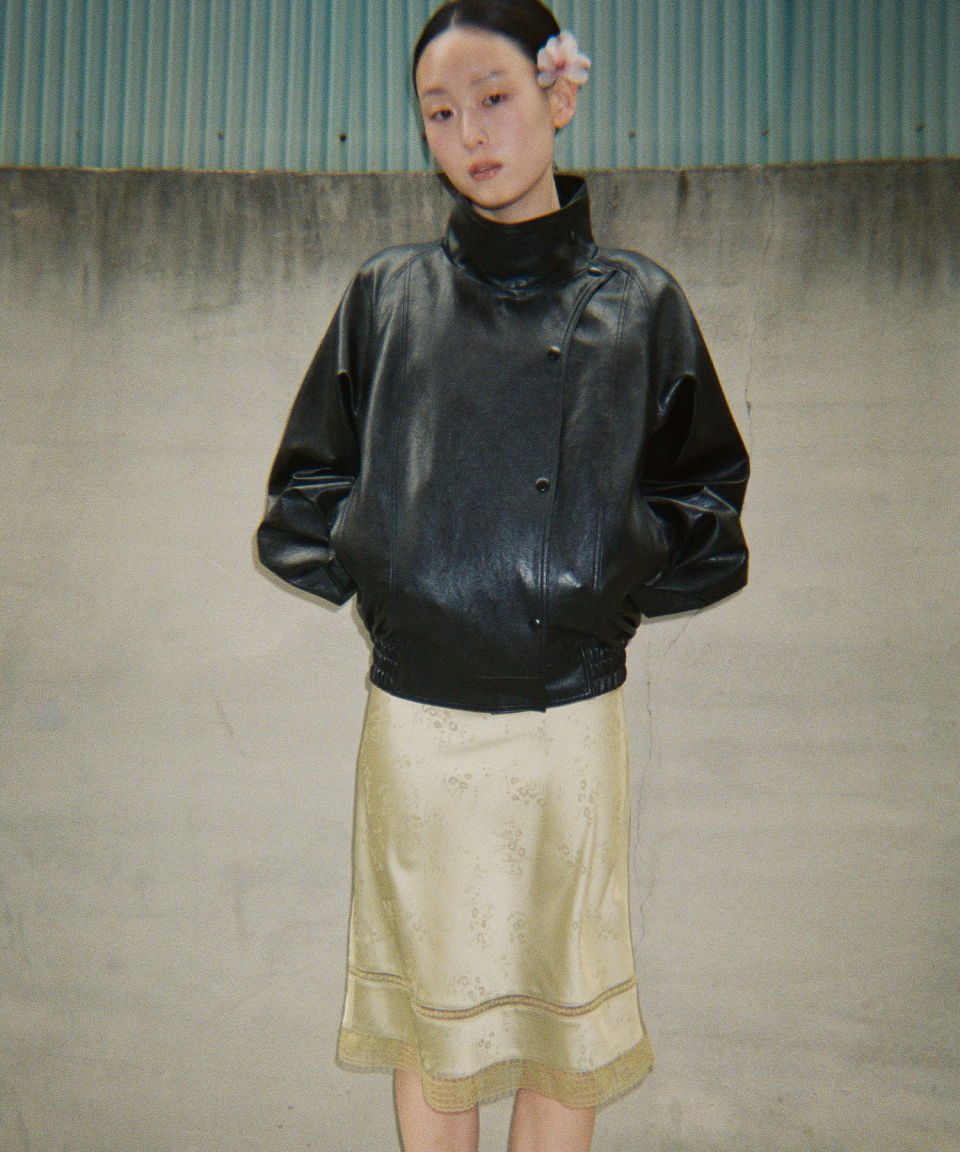 모델이 검정색 와이드 카라 인조 가죽 자켓을 입고있다.