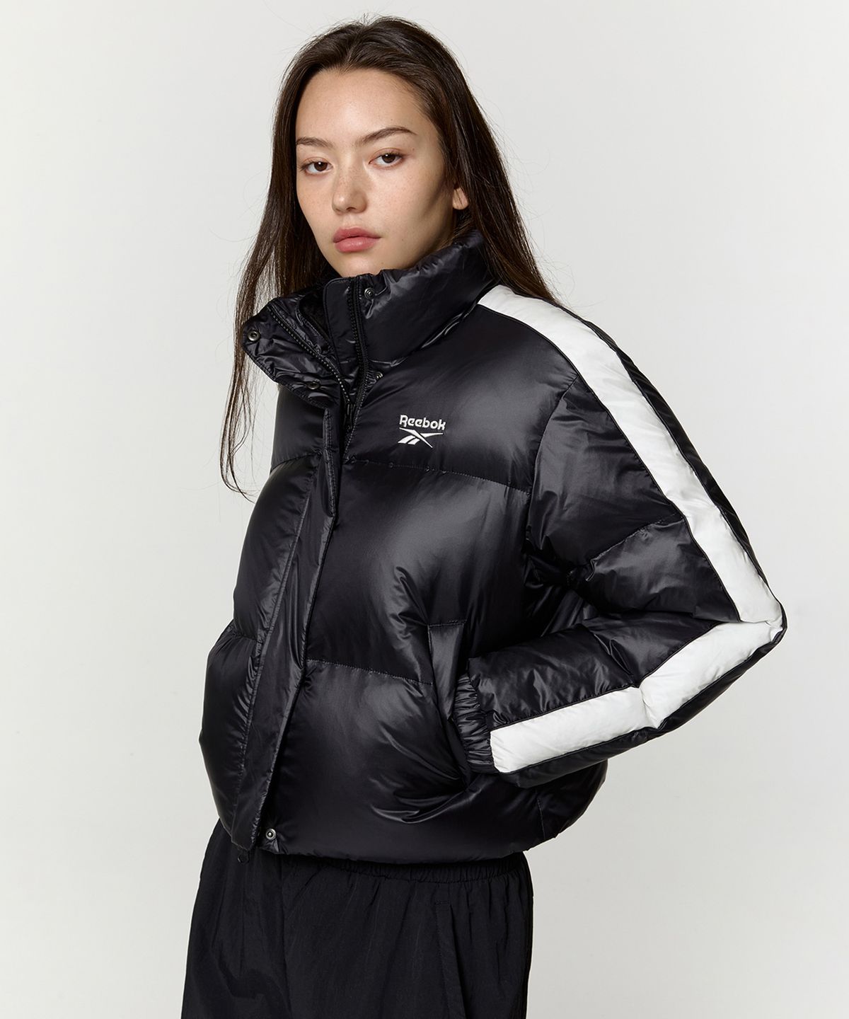 리복(REEBOK) 글로시 패널드 크롭 다운 자켓 (W) - 블랙