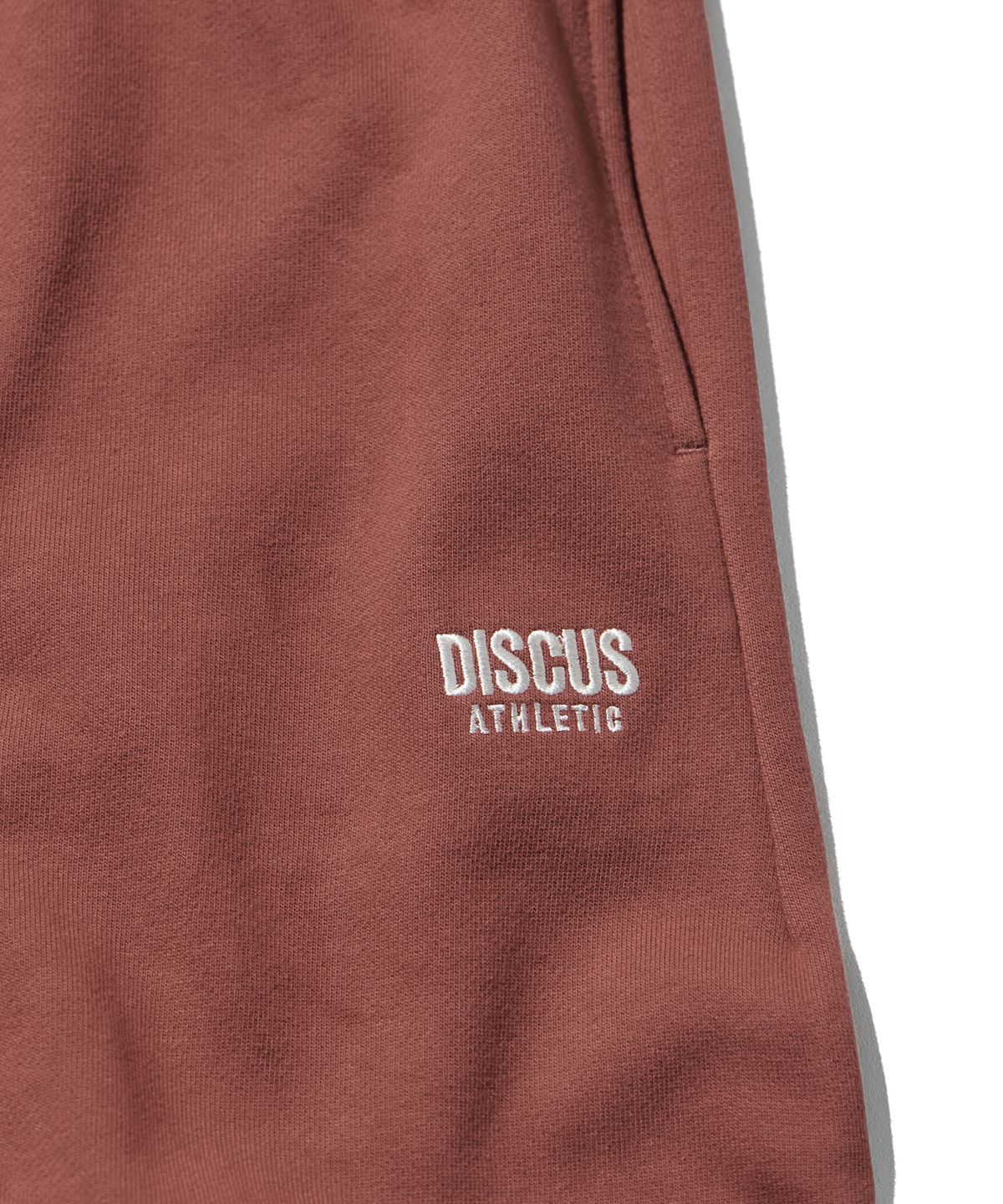디스커스 애슬레틱(DISCUS ATHLETIC) 헤비웨이트 레터 로고 스웨트 팬츠 브릭 레드