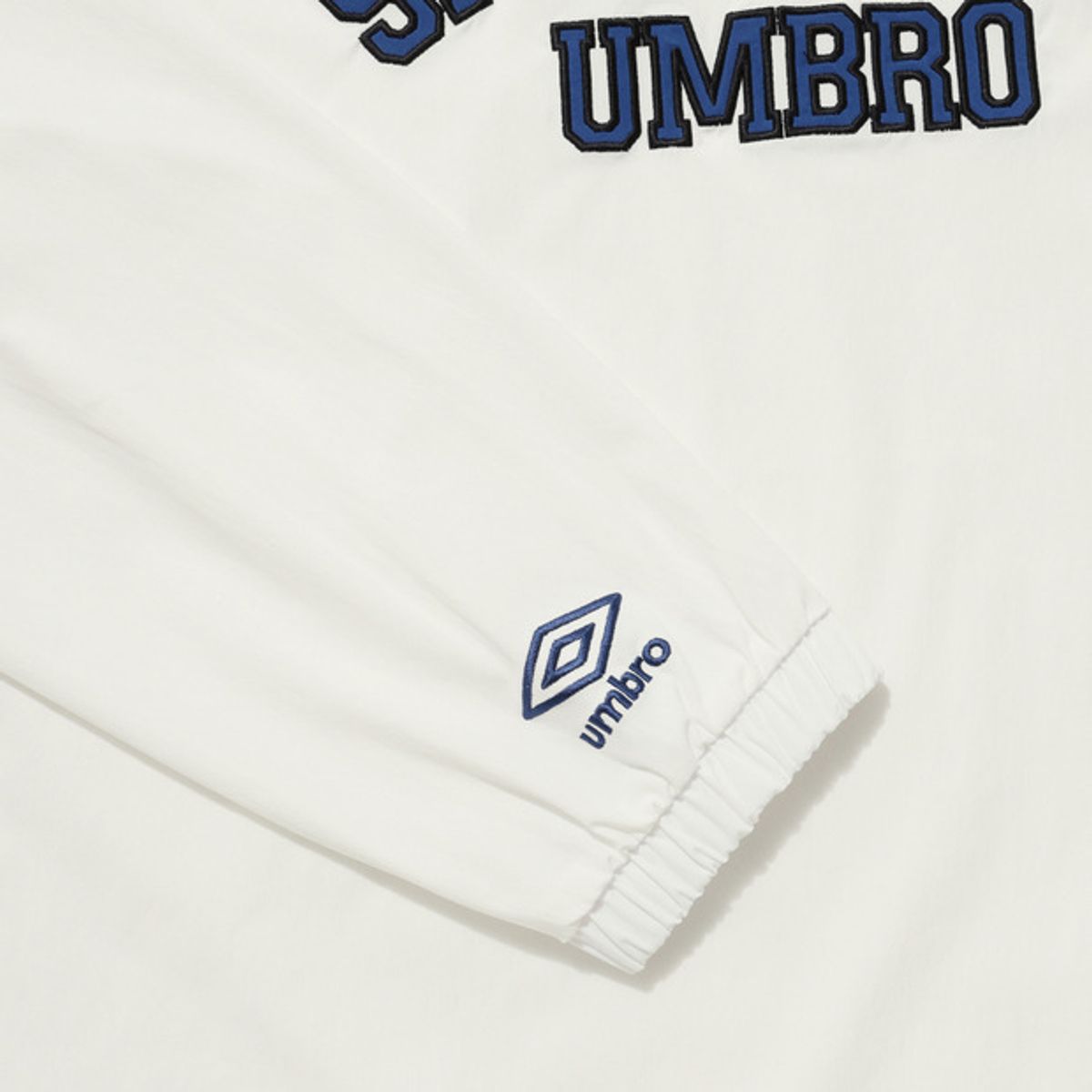 엄브로(UMBRO) 아치 레터링 자수 피스테 아이보리(UQ321CWT90)
