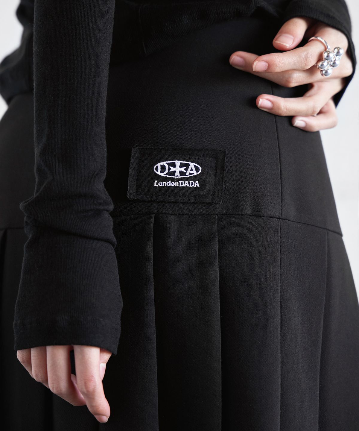 런던다다(LONDONDADA) LOGO PATCHED BUCKLE PLEATS SKIRT, BLACK