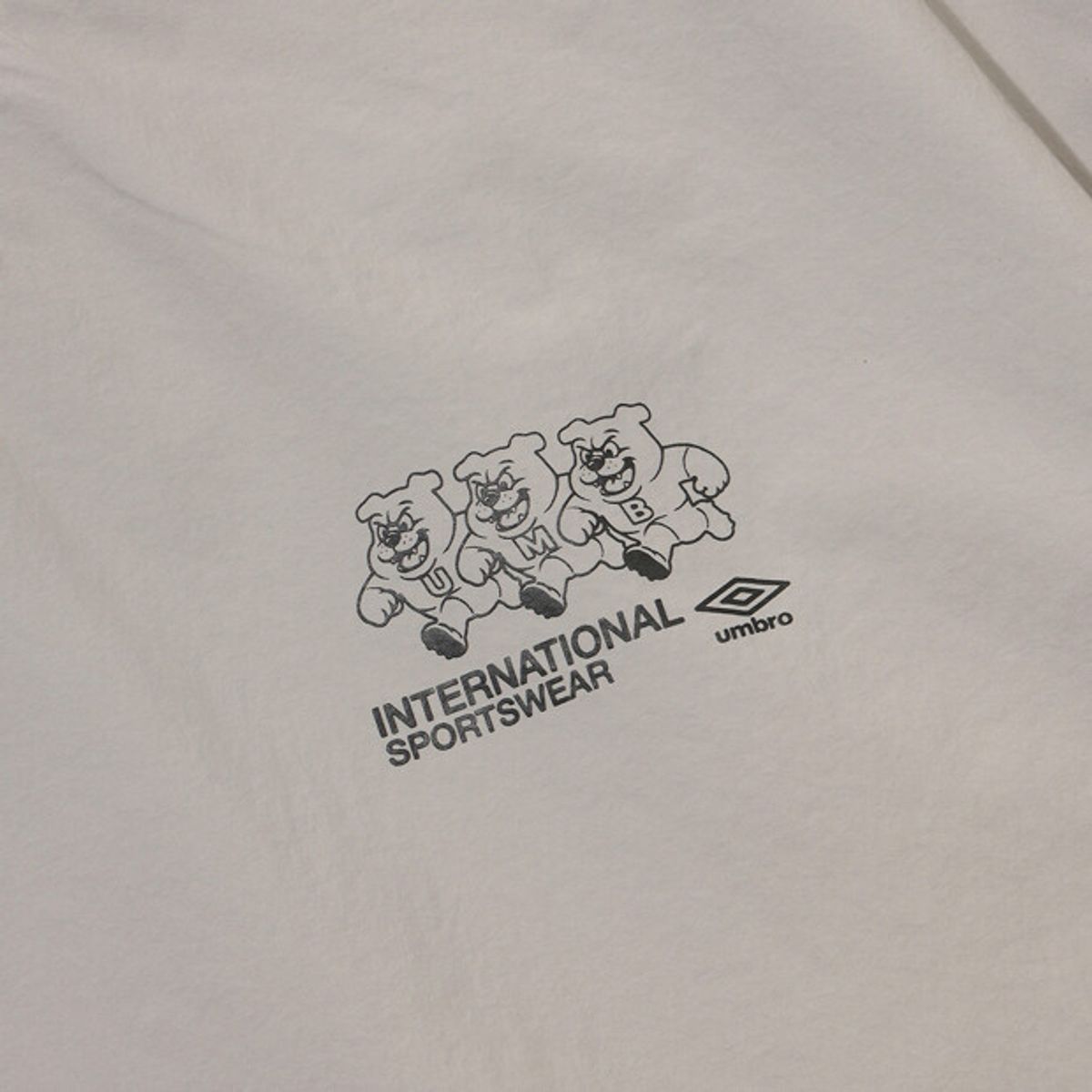 엄브로(UMBRO) 팝러쉬 더비독 그래픽 긴팔 피스테 베이지 UR121CWT35