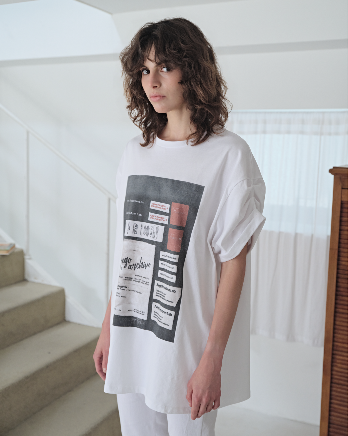 이고프리덤랩(AEGO FREEDOM LAB) 턱 롤업 슬리브 그래픽 티_화이트