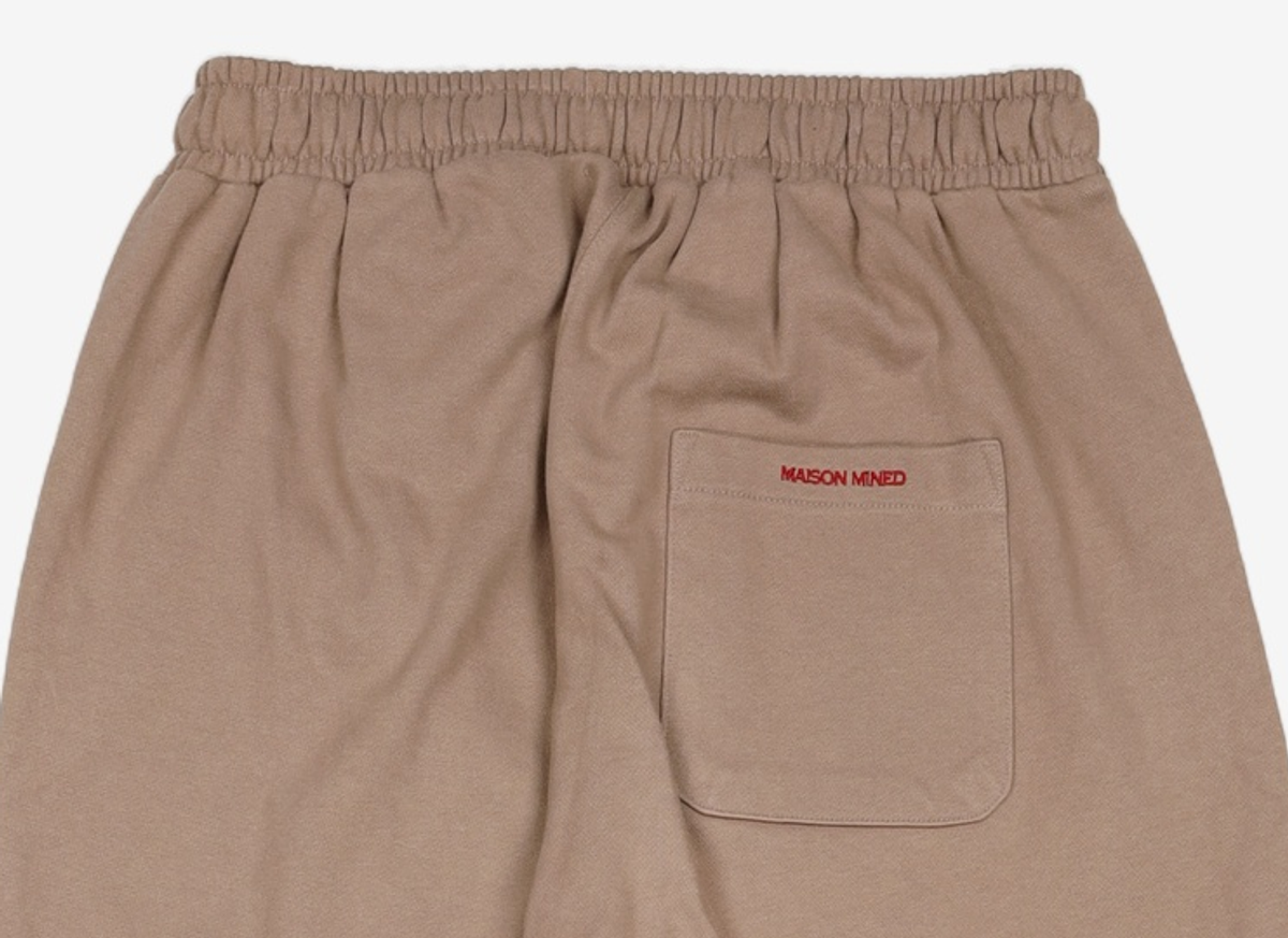 메종미네드(MAISON MINED) (THE LION KING)SMALL LOGO JOGGER PANTS DUSTY BEIGE 50