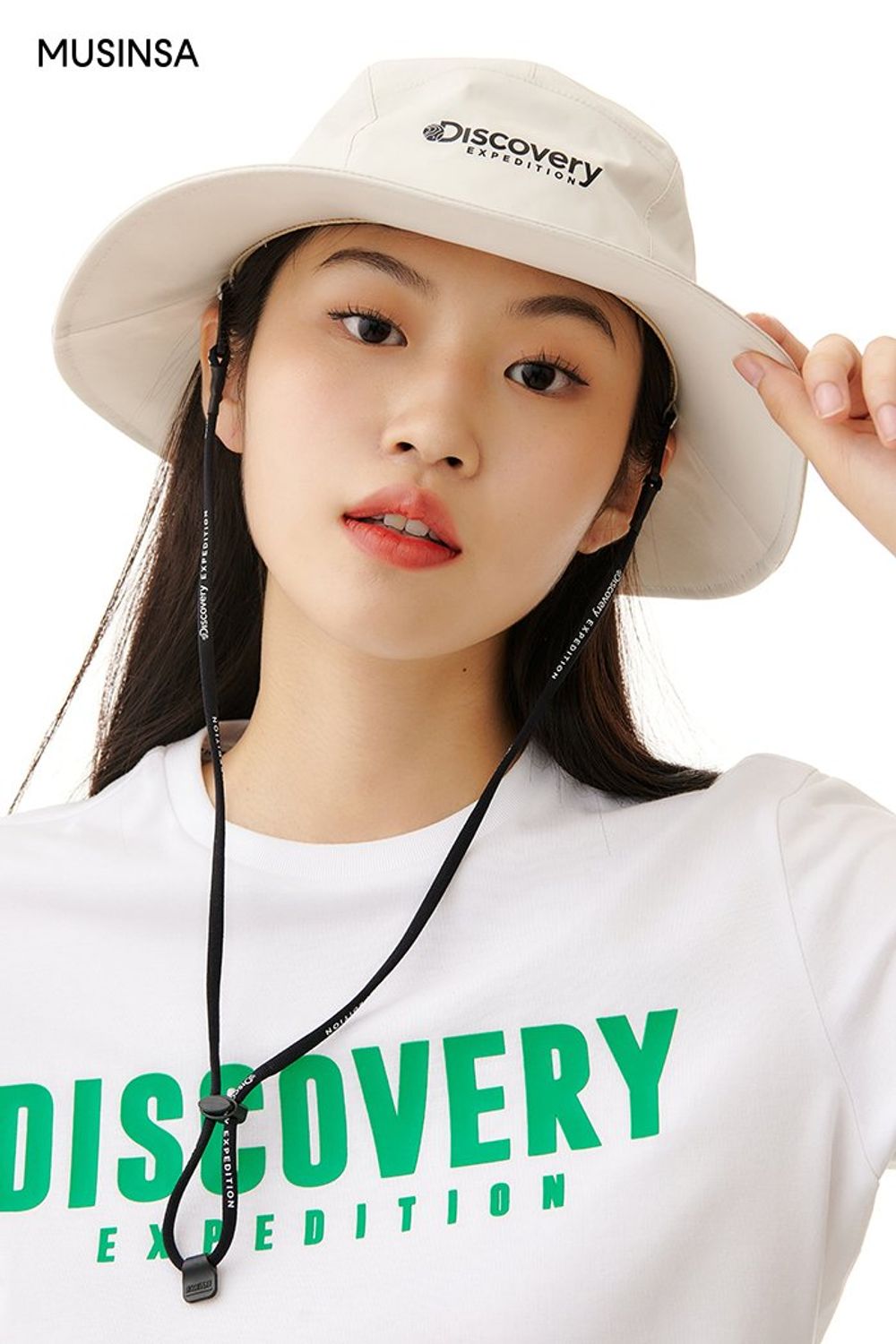 로고 프린팅이 돋보이는 반소매 티셔츠에 벨티드 스커트를 코디한 후 사파리 햇으로 캠핑 무드를 더한 스포츠 룩 #로고플레이 #캠핑 #레저스포츠 #스포티 #뉴트럴톤 #고프코어 #여름